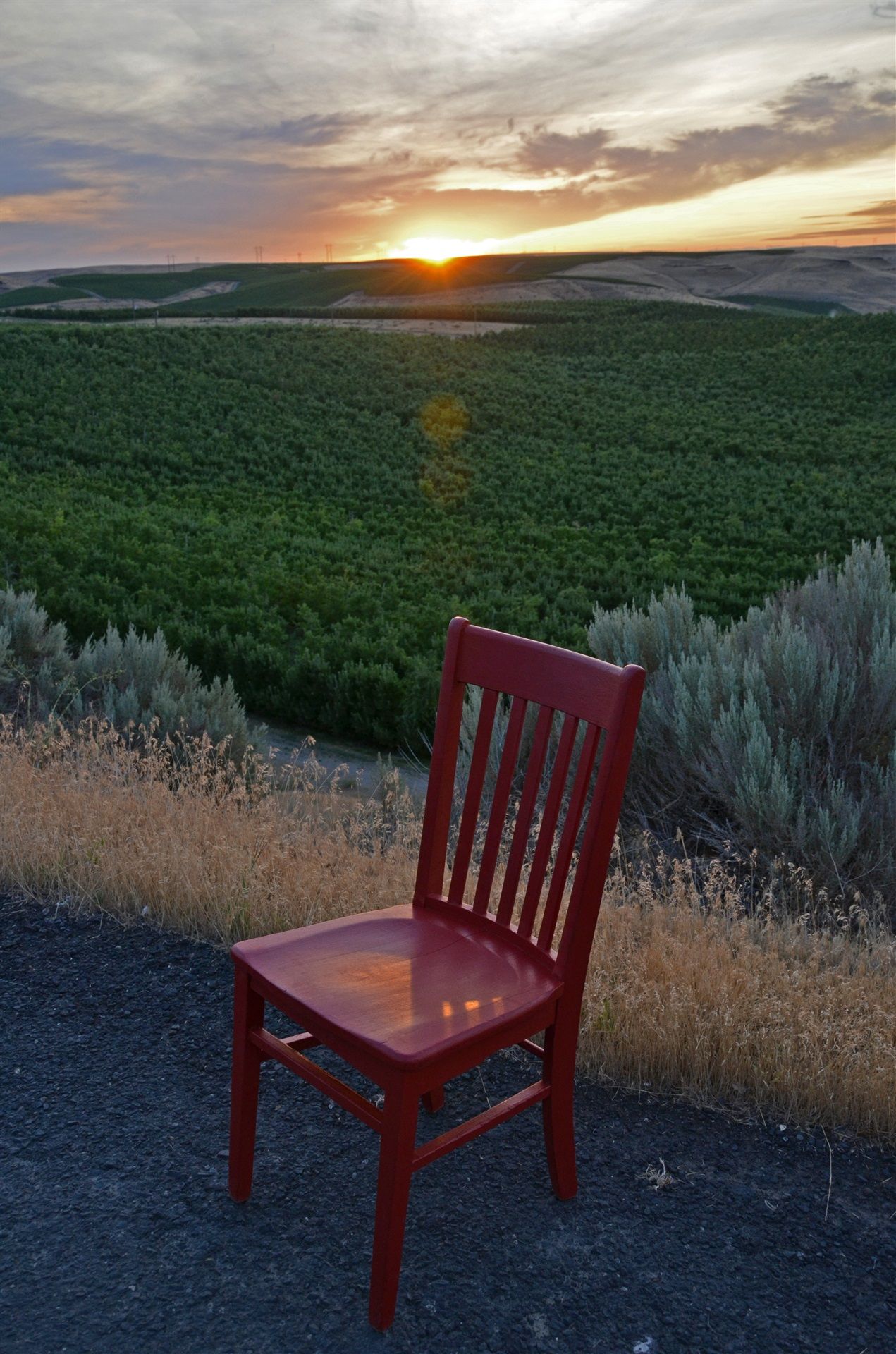 Red chair on gravel road overlooking the forests and mountain during the sunrise
