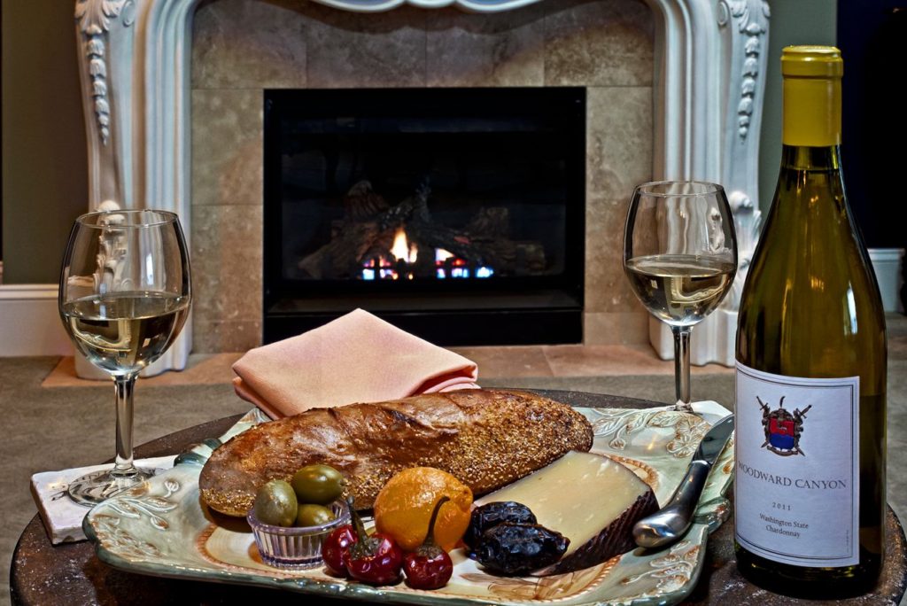 Greek Suite fireplace with plated dinner and two glasses of Chardonnay with the bottle beside the plate