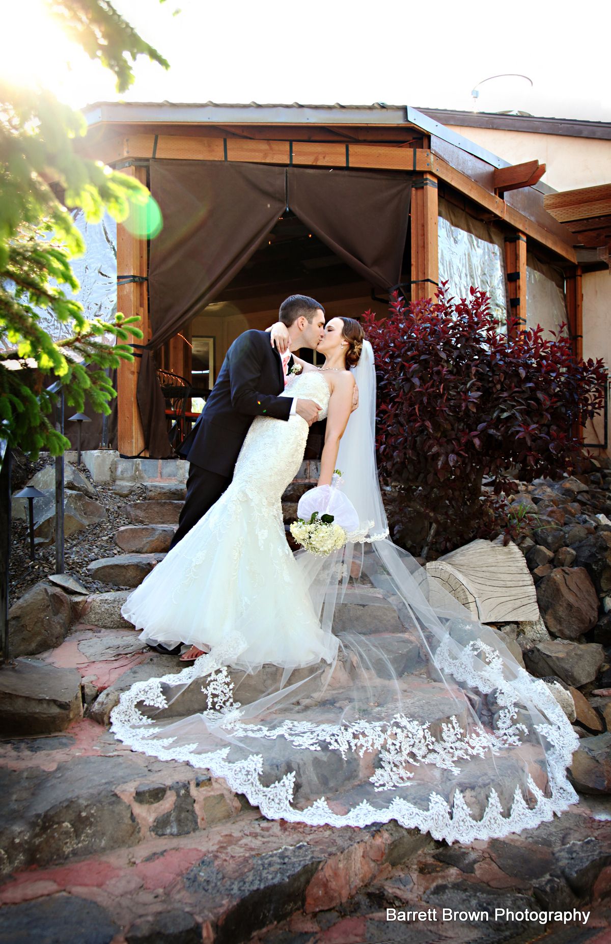 Groom dipping bride as the couple kiss on a stone staircase