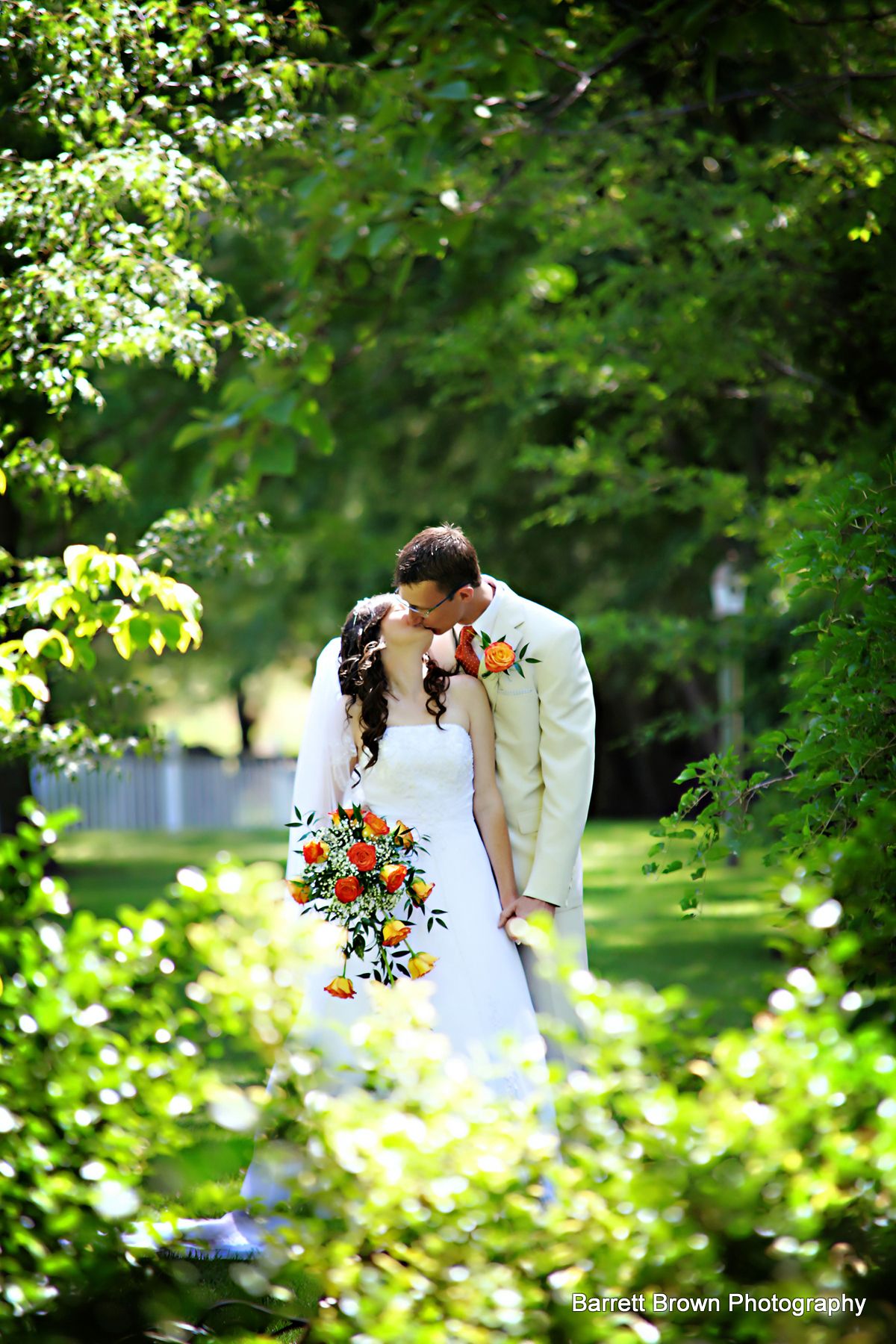 Bride and groom kissing in a lightly forested field